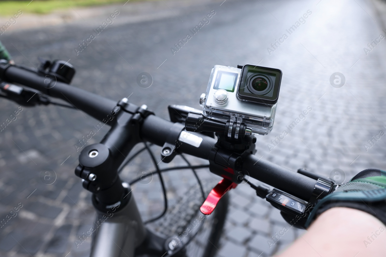 Photo of Man riding bicycle with modern action camera outdoors, closeup