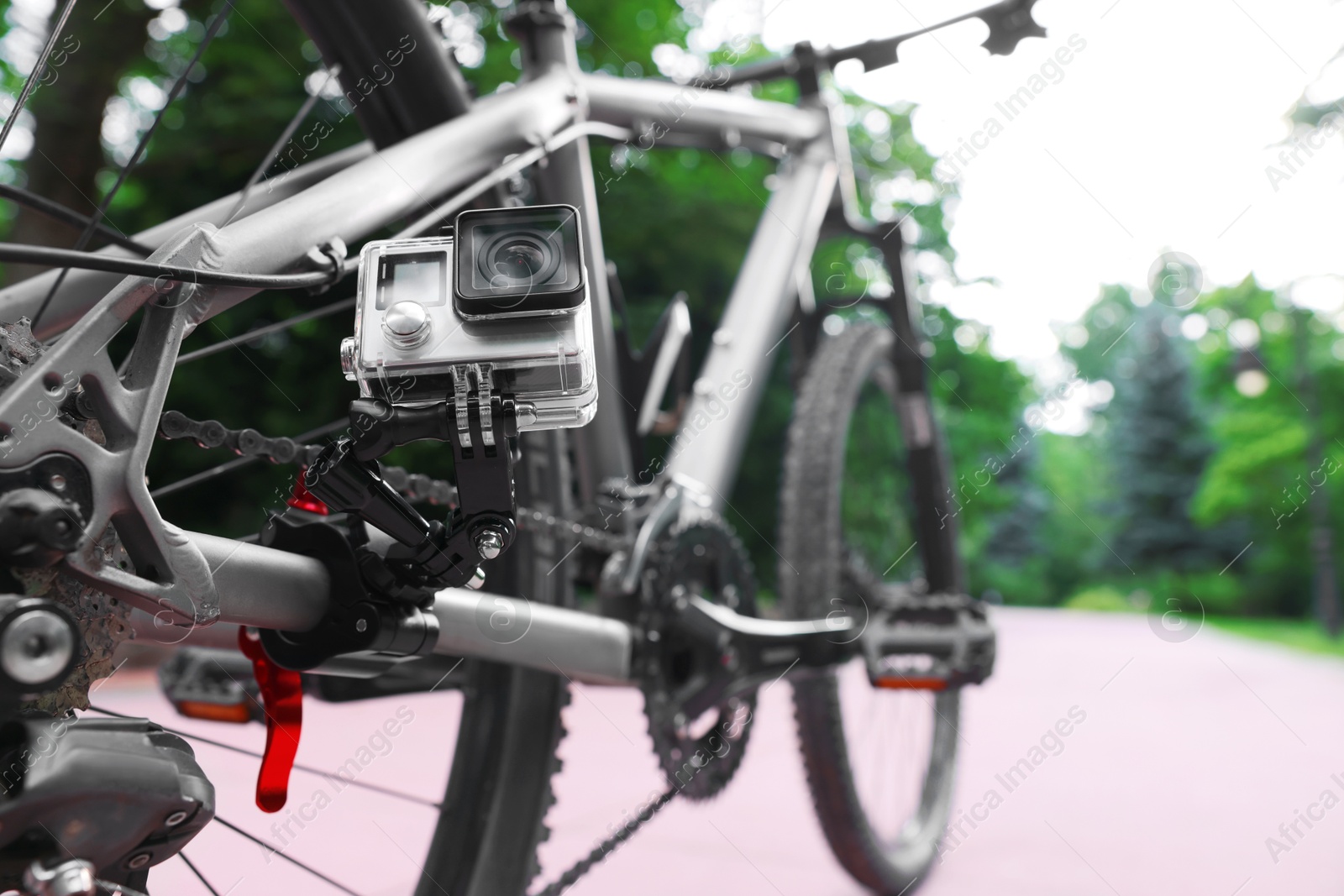 Photo of Modern action camera with mount on bicycle outdoors, closeup. Space for text