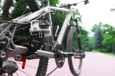 Modern action camera with mount on bicycle outdoors, closeup. Space for text