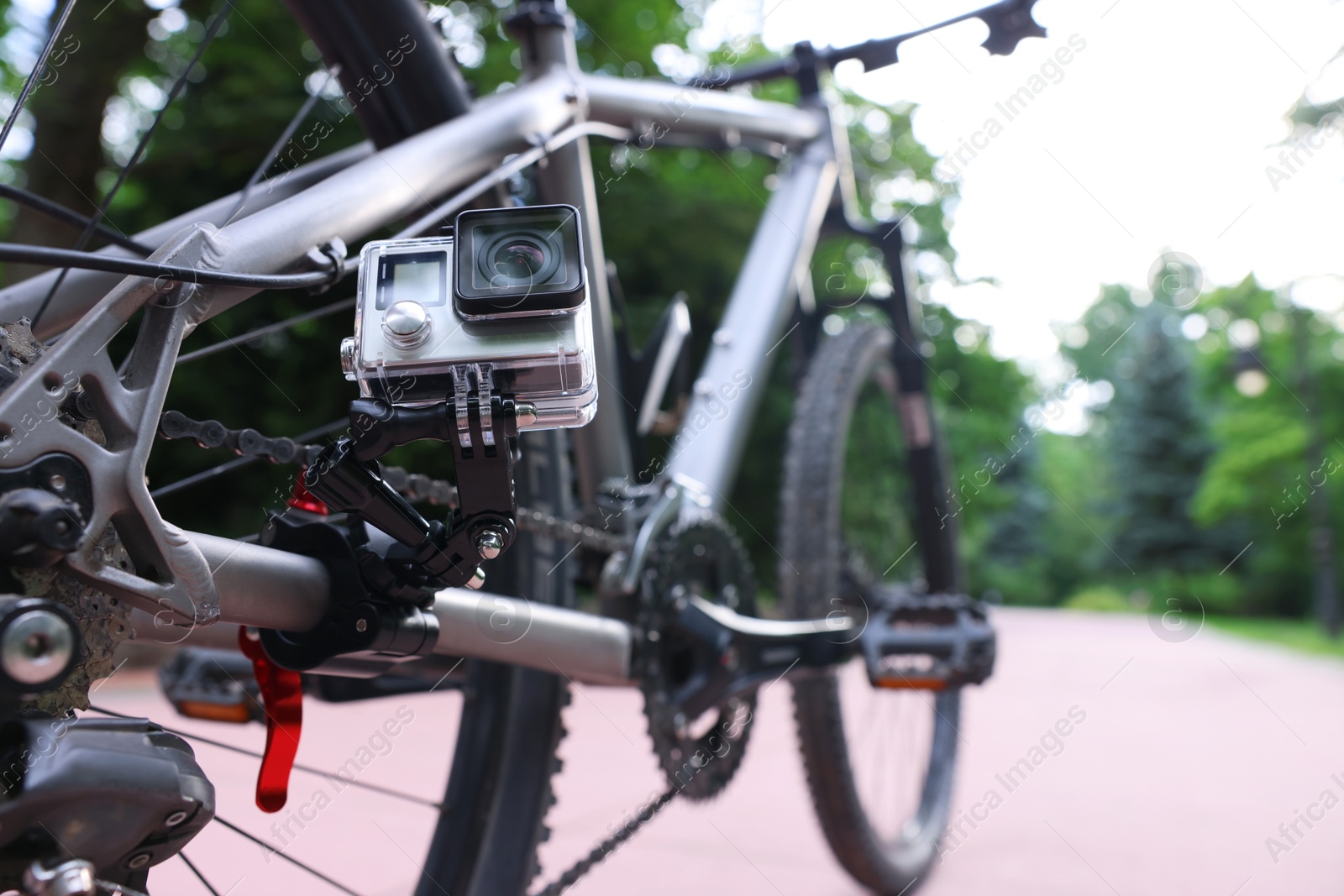 Photo of Modern action camera with mount on bicycle outdoors, closeup. Space for text