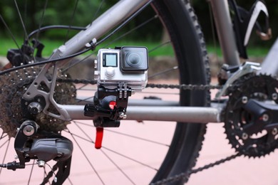 Photo of Modern action camera with mount on bicycle outdoors, closeup