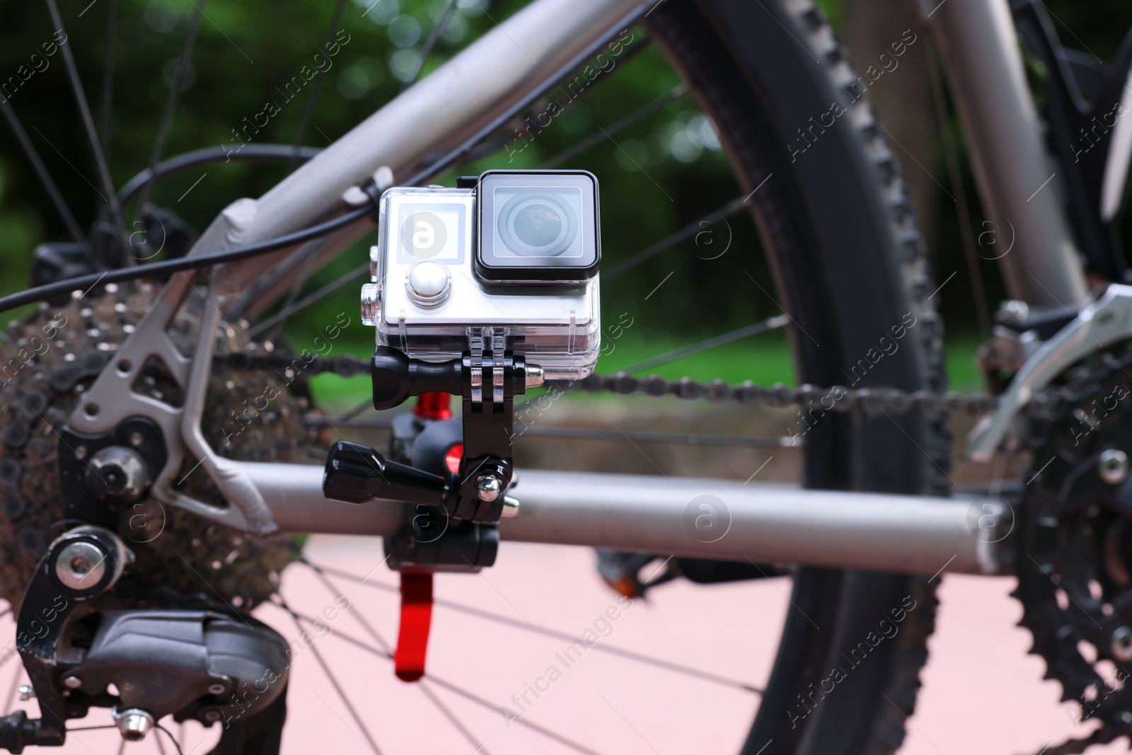 Photo of Modern action camera with mount on bicycle outdoors, closeup