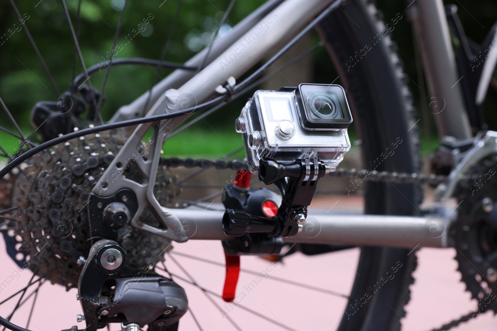 Photo of Modern action camera with mount on bicycle outdoors, closeup