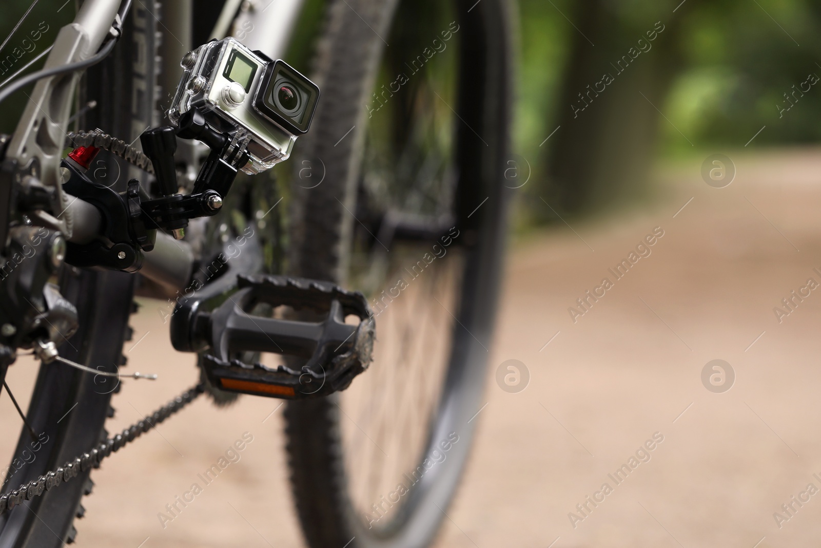 Photo of Modern action camera with mount on bicycle outdoors. Space for text