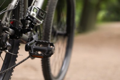 Modern action camera with mount on bicycle outdoors. Space for text