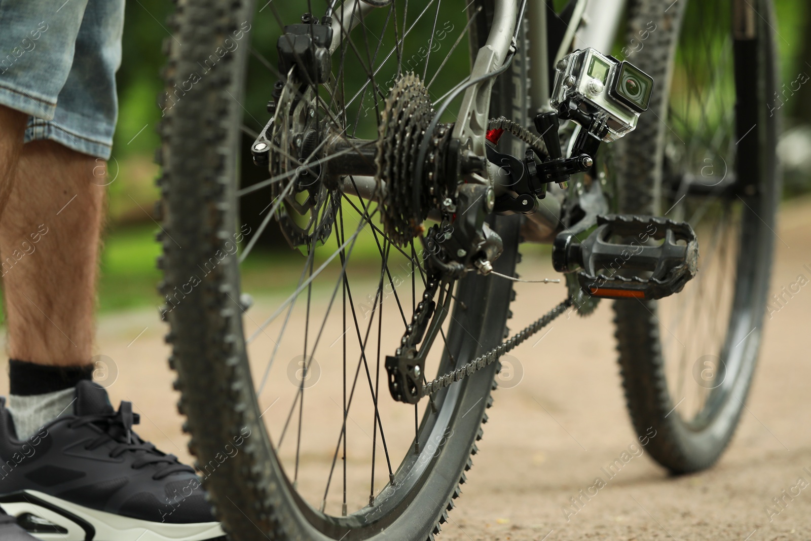 Photo of Man near bicycle with modern action camera outdoors, closeup