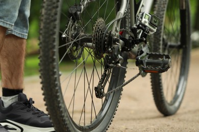 Man near bicycle with modern action camera outdoors, closeup