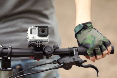 Man riding bicycle with modern action camera outdoors, closeup