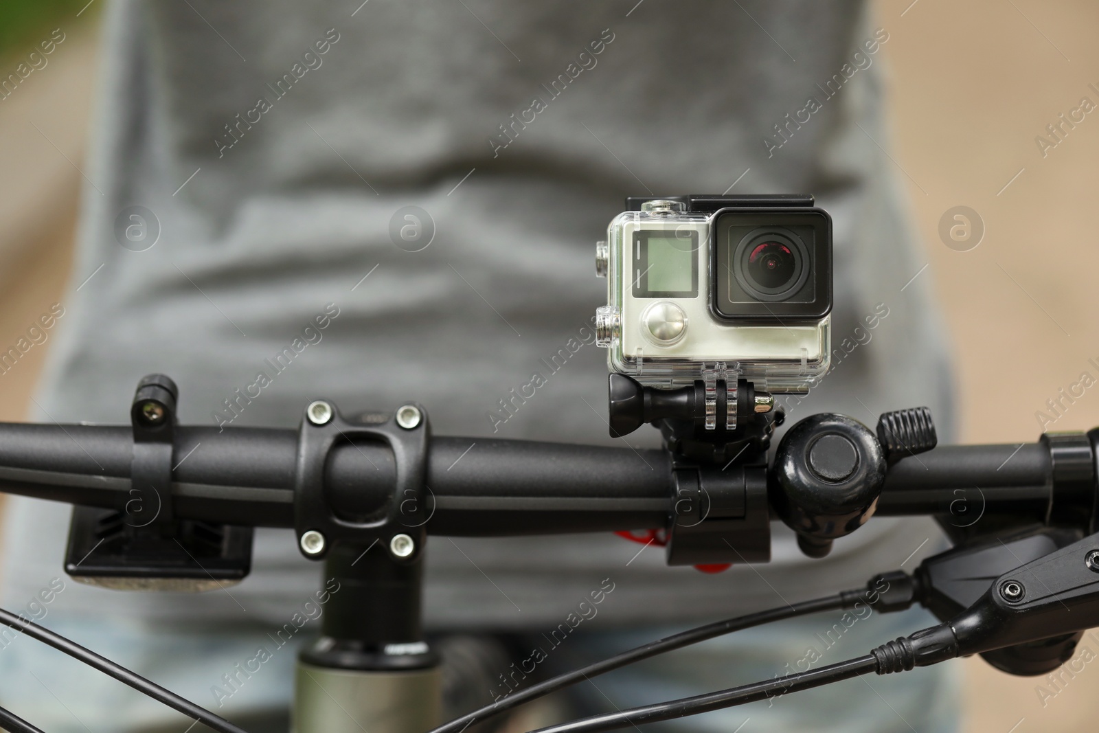 Photo of Man riding bicycle with modern action camera outdoors, closeup