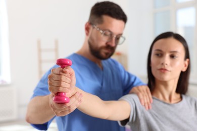 Patient exercising under physiotherapist supervision in rehabilitation center, selective focus