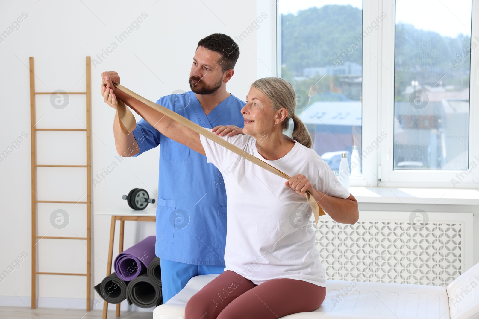 Photo of Senior patient exercising under physiotherapist supervision in rehabilitation center