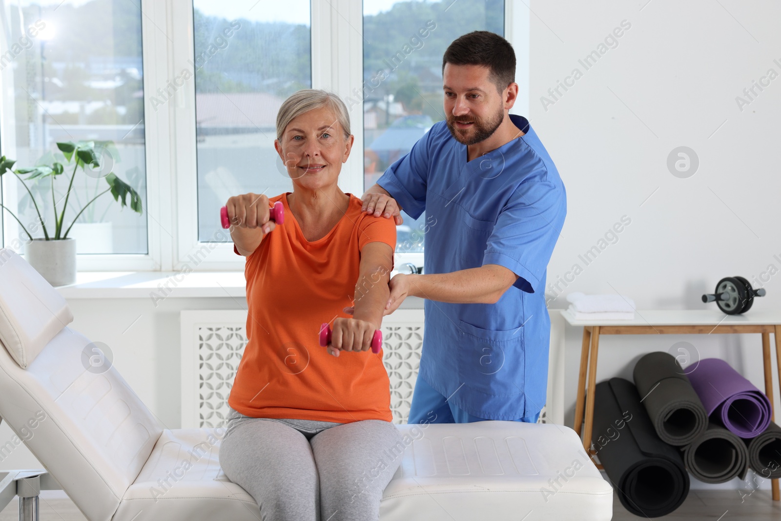 Photo of Senior patient exercising under physiotherapist supervision in rehabilitation center