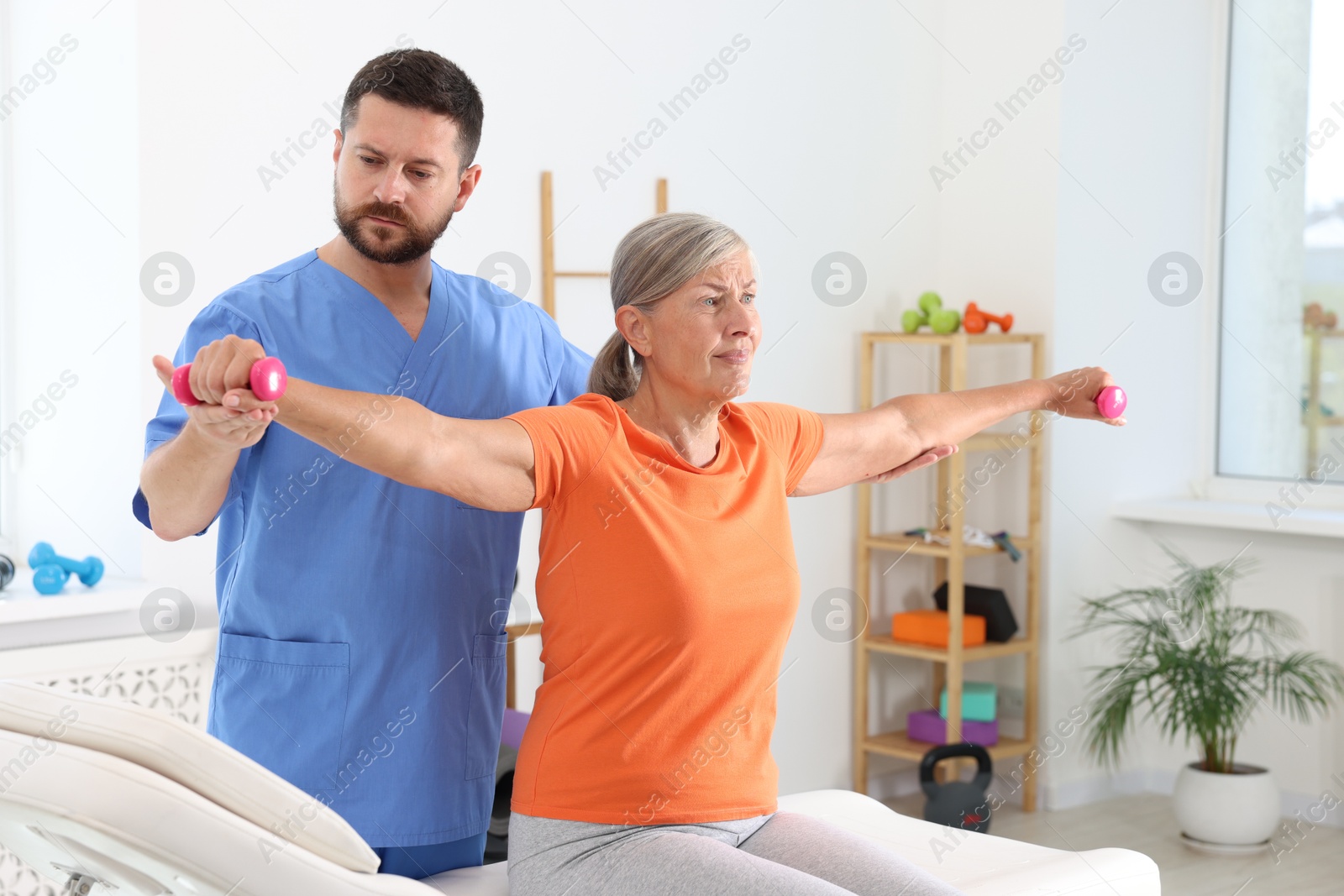 Photo of Senior patient exercising under physiotherapist supervision in rehabilitation center