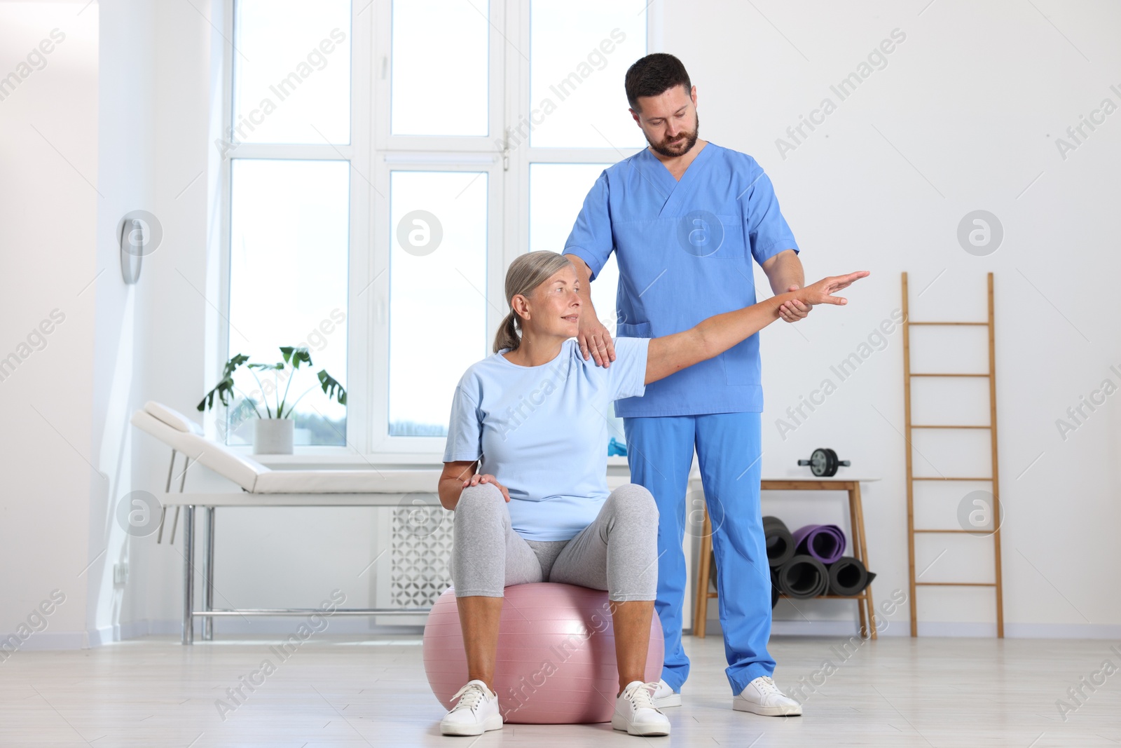 Photo of Physiotherapist working with senior patient in rehabilitation center