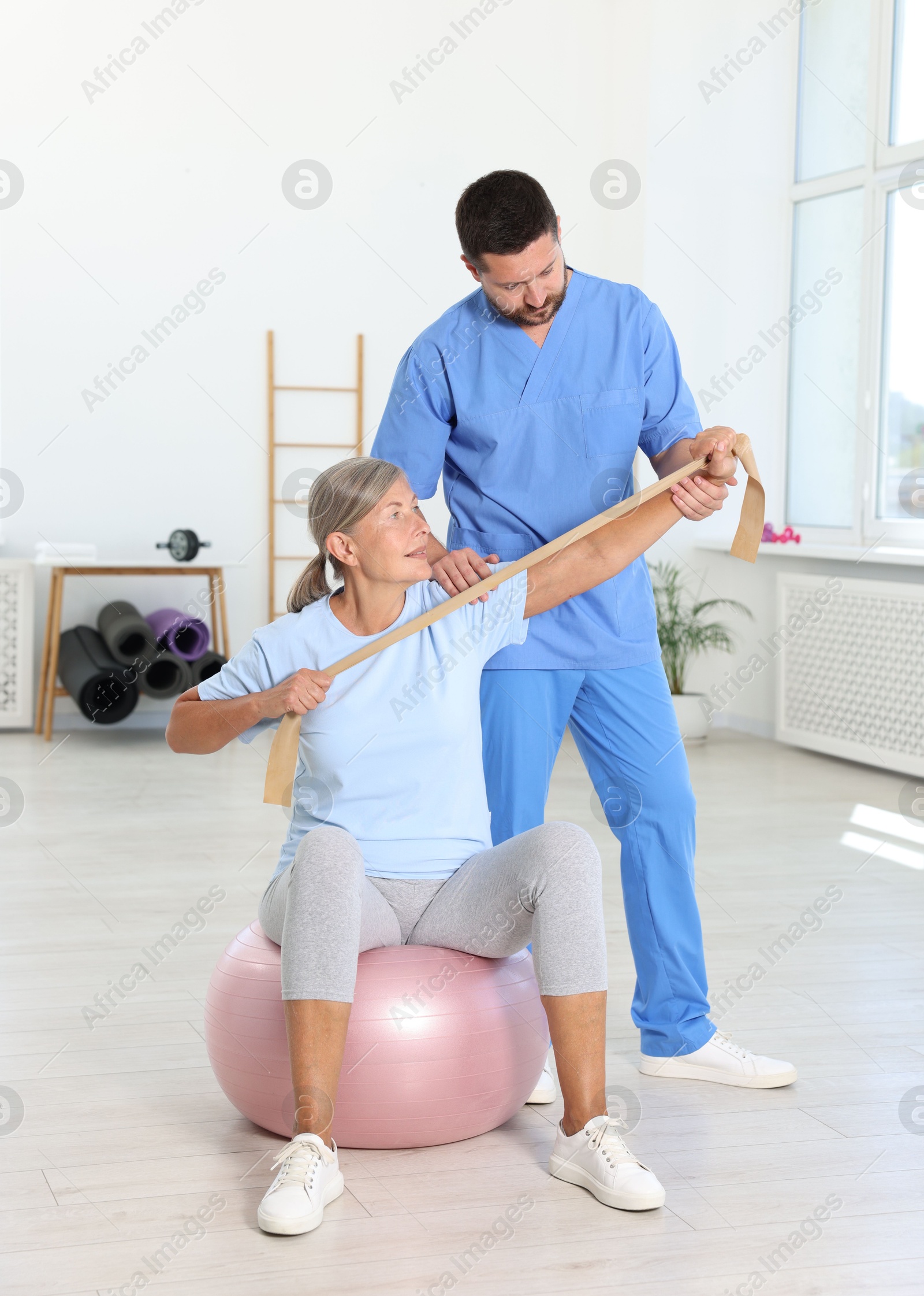 Photo of Senior patient exercising under physiotherapist supervision in rehabilitation center