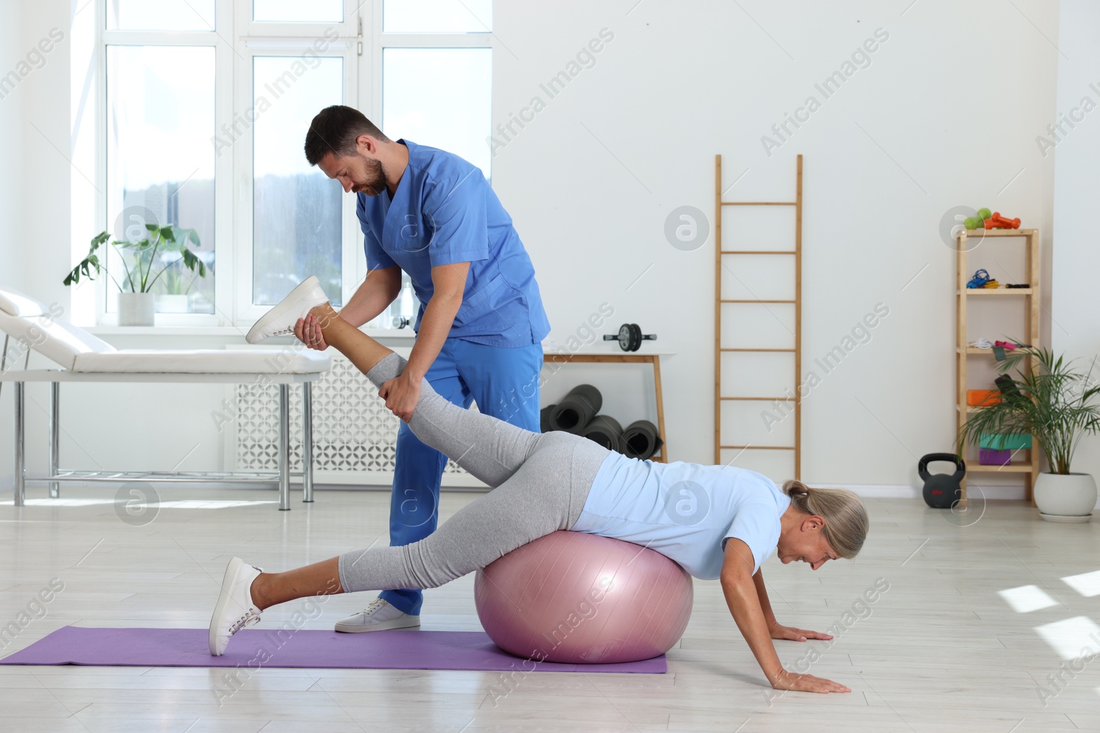 Photo of Physiotherapist working with senior patient in rehabilitation center