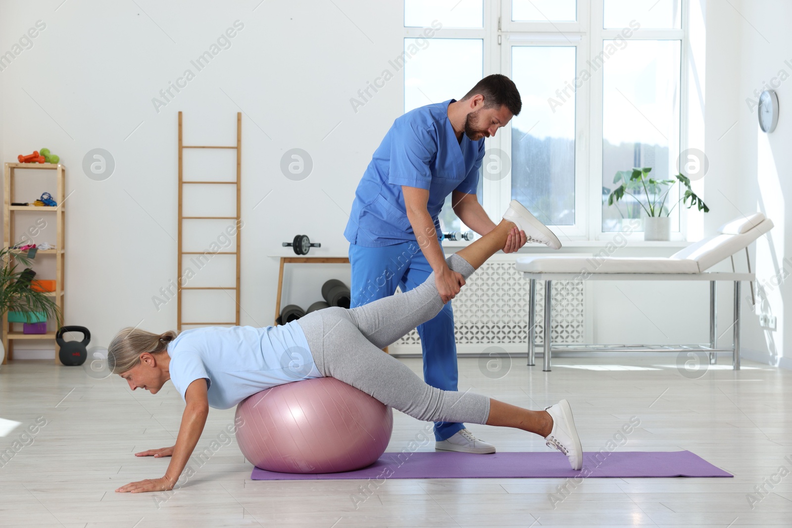 Photo of Physiotherapist working with senior patient in rehabilitation center