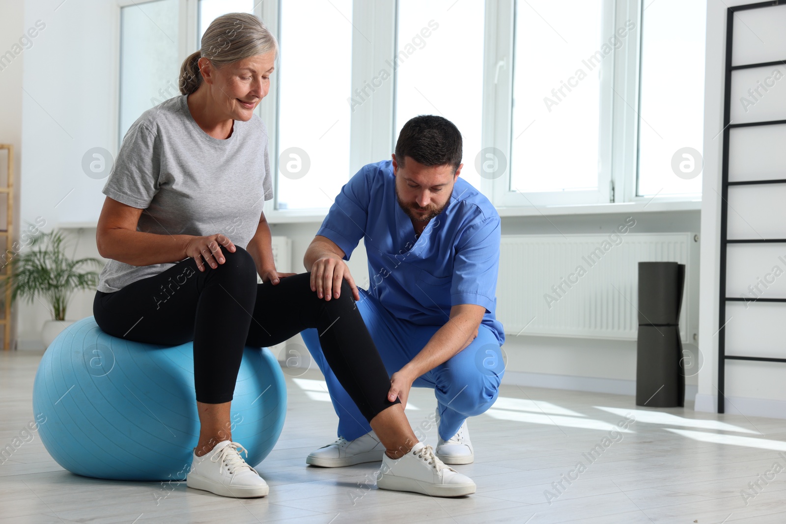 Photo of Physiotherapist working with senior patient in rehabilitation center