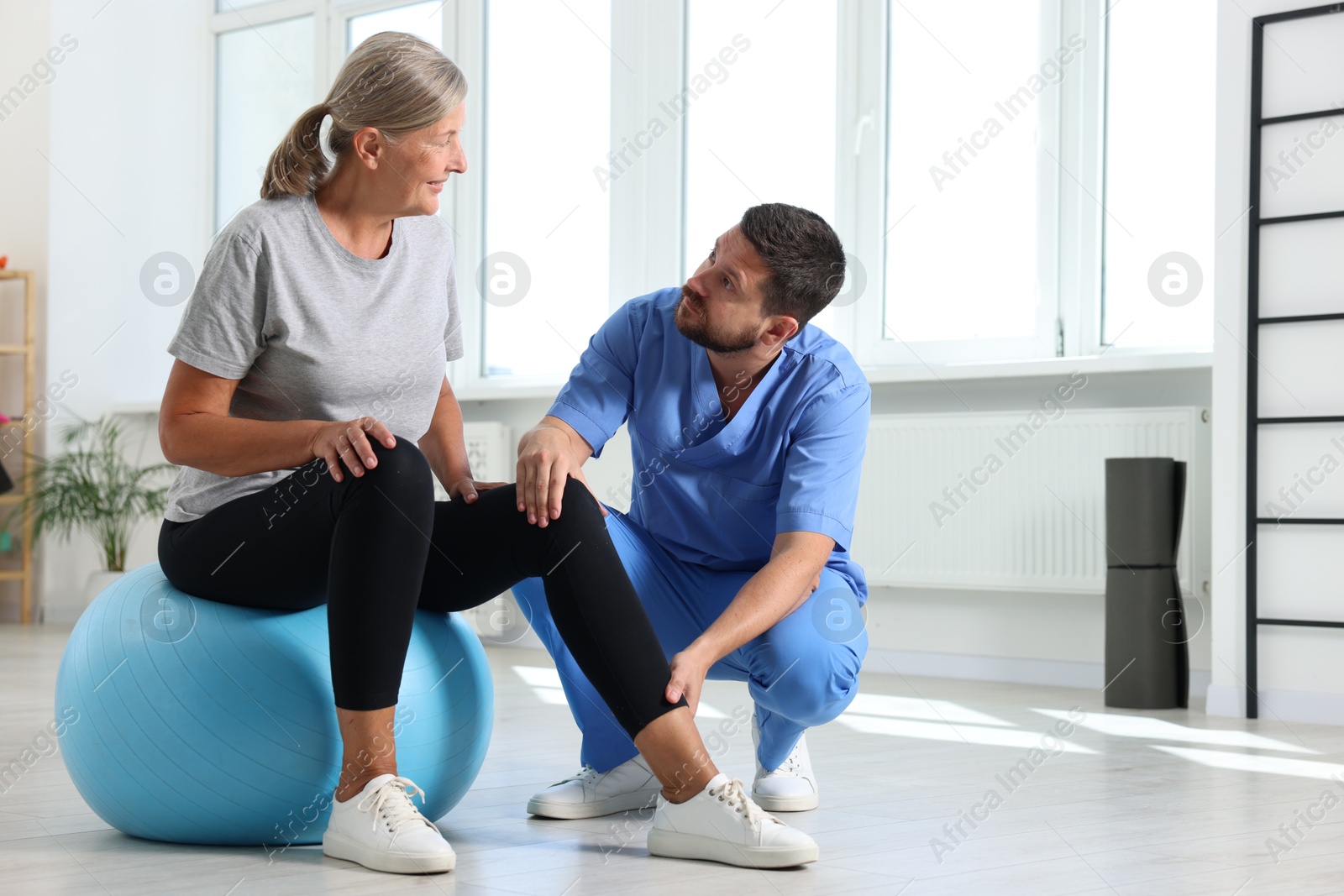 Photo of Physiotherapist working with senior patient in rehabilitation center