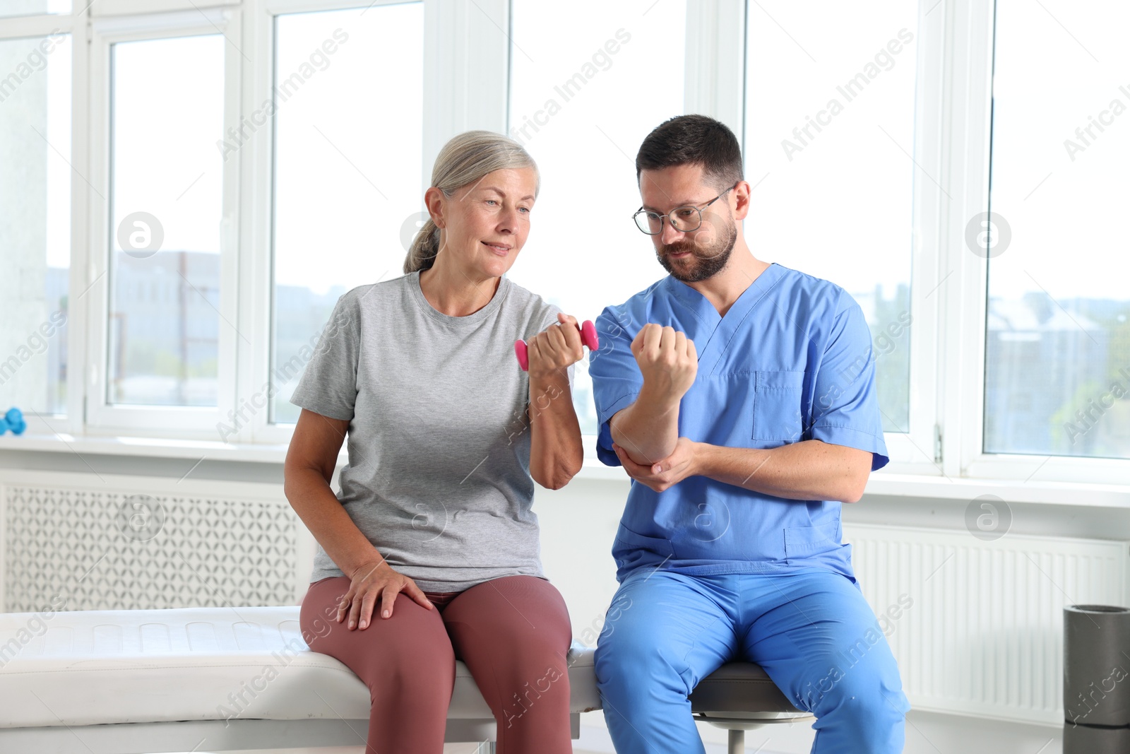 Photo of Senior patient exercising under physiotherapist supervision in rehabilitation center