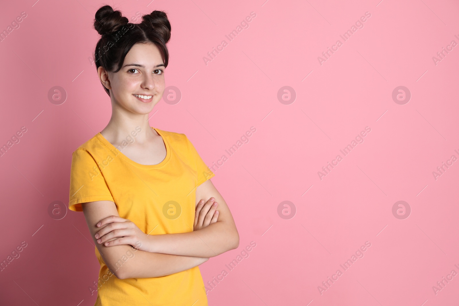 Photo of Portrait of smiling teenage girl on pink background. Space for text