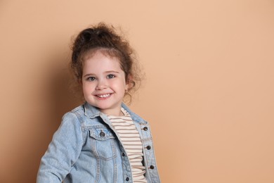 Adorable child. Portrait of happy girl on beige background, space for text