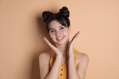 Portrait of smiling teenage girl on beige background