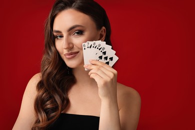 Photo of Poker game. Charming woman with playing cards on red background. Space for text