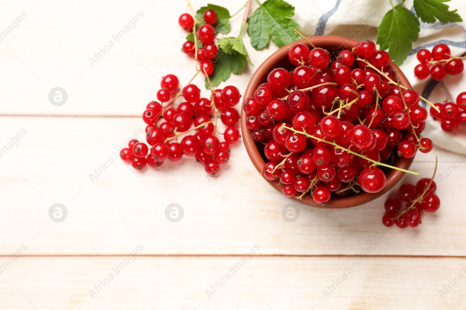 Photo of Fresh red currant berries in bowl on white wooden table, top view. Space for text