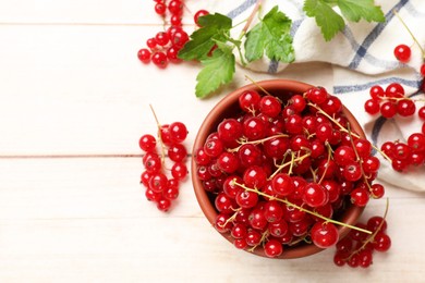 Photo of Fresh red currant berries in bowl on white wooden table, top view. Space for text