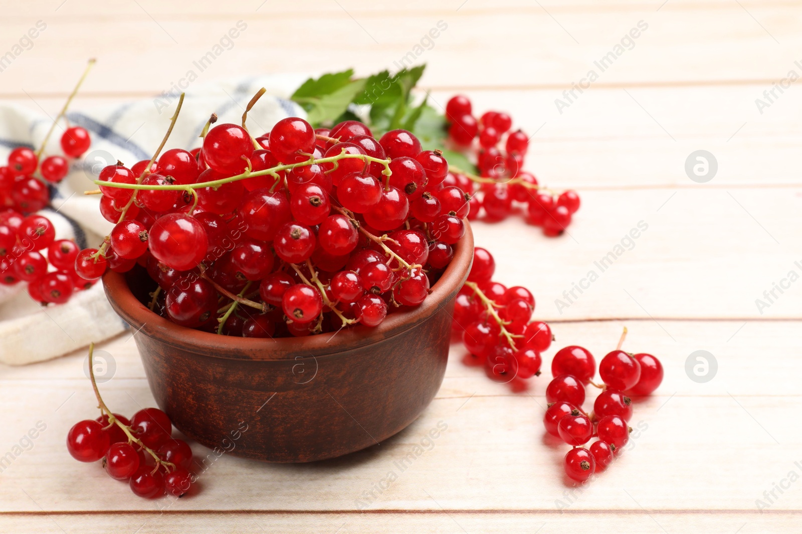 Photo of Fresh red currant berries in bowl on white wooden table, closeup