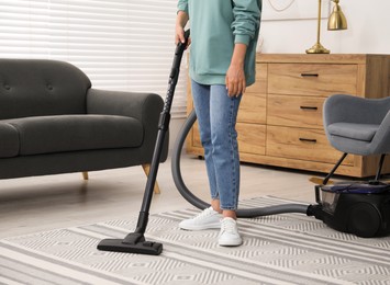 Photo of Woman vacuuming carpet at home, closeup view