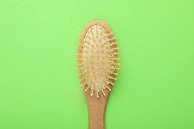 Photo of One brush with lost hair on light green background, top view