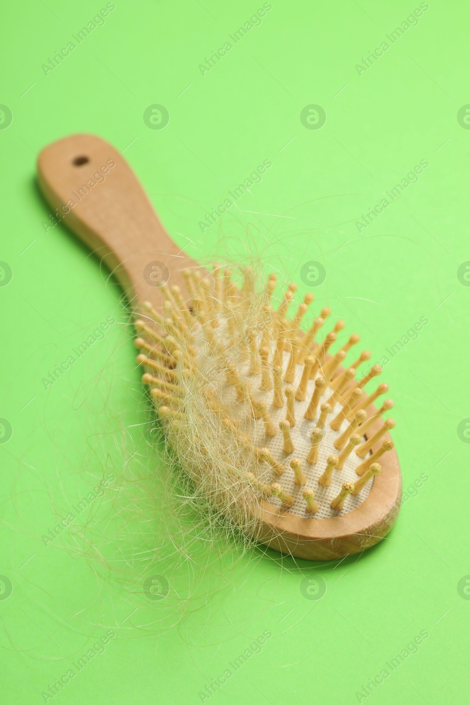 Photo of One brush with lost hair on light green background. Alopecia problem