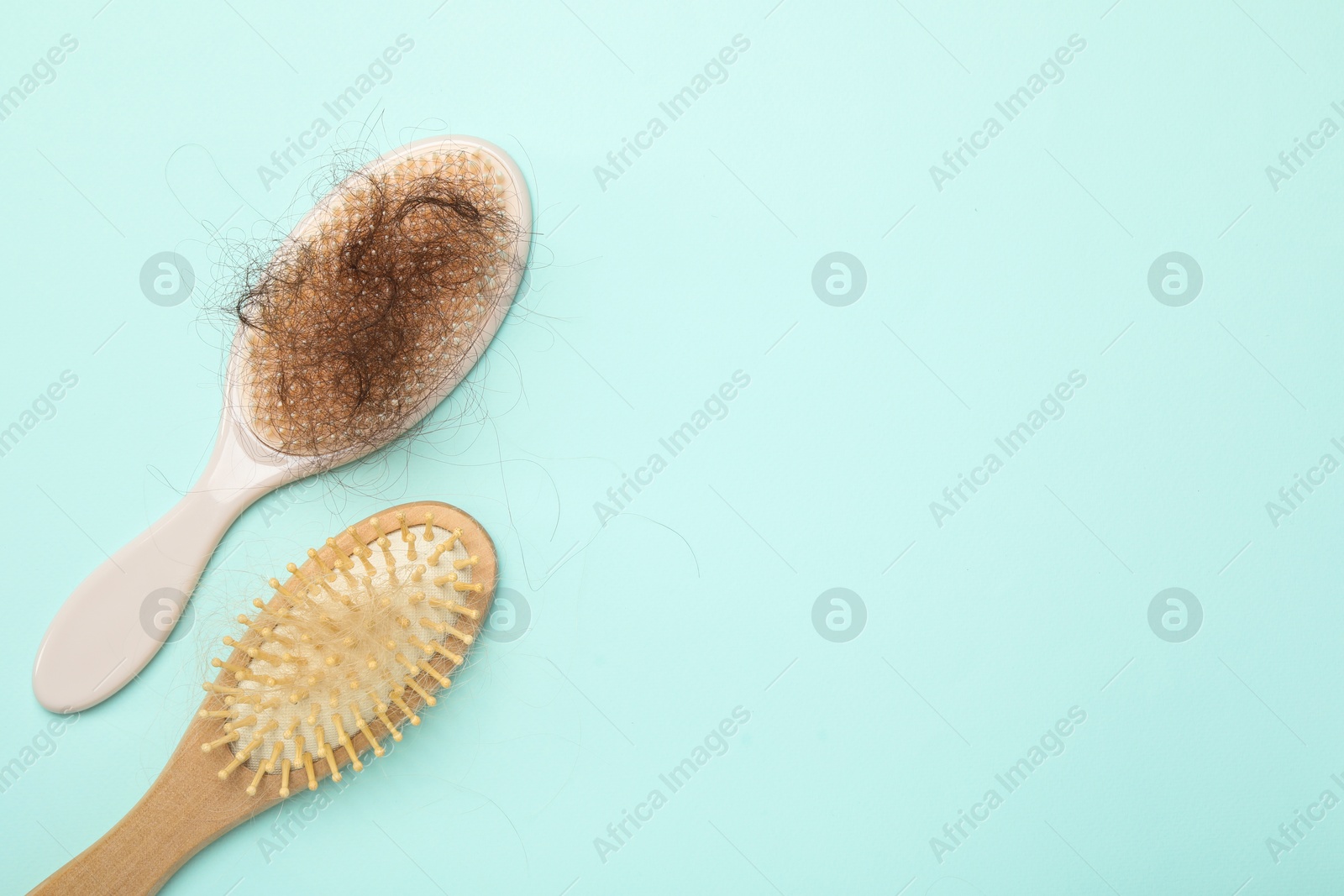 Photo of Brushes with lost hair on light blue background, flat lay. Space for text