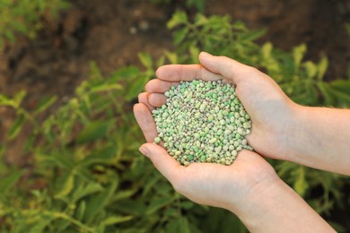 Photo of Woman holding green plant fertilizer outdoors, closeup. Space for text