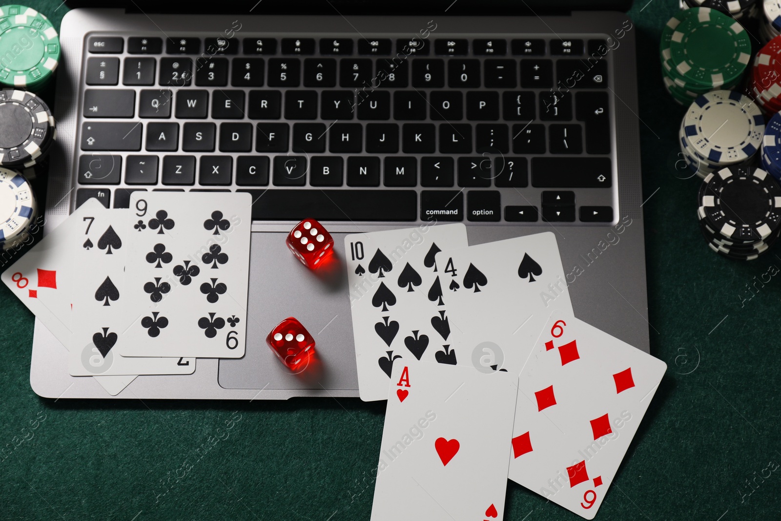 Photo of Laptop, poker chips, dices and playing cards on green table, above view. Online game