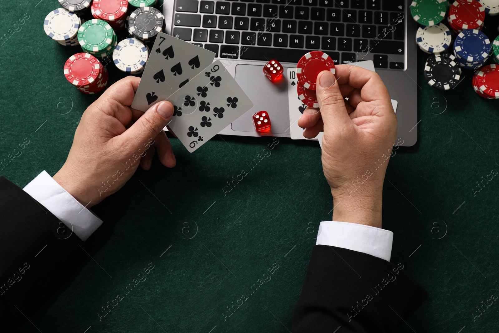 Photo of Man with laptop playing poker at green table, top view. Online game