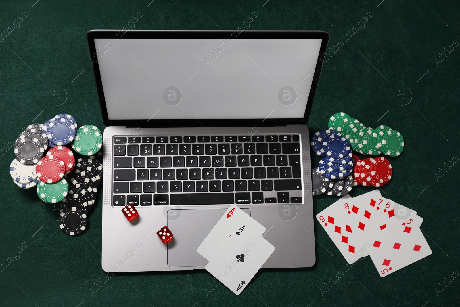 Photo of Laptop, poker chips, dices and playing cards on green table, top view. Online game