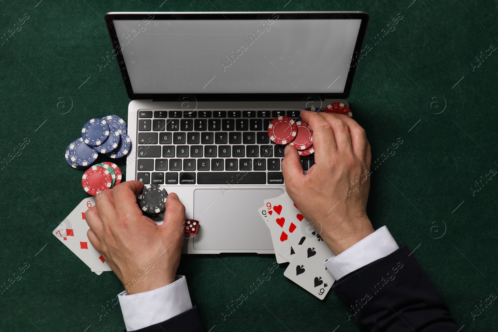 Photo of Man with laptop playing poker at green table, top view. Online game