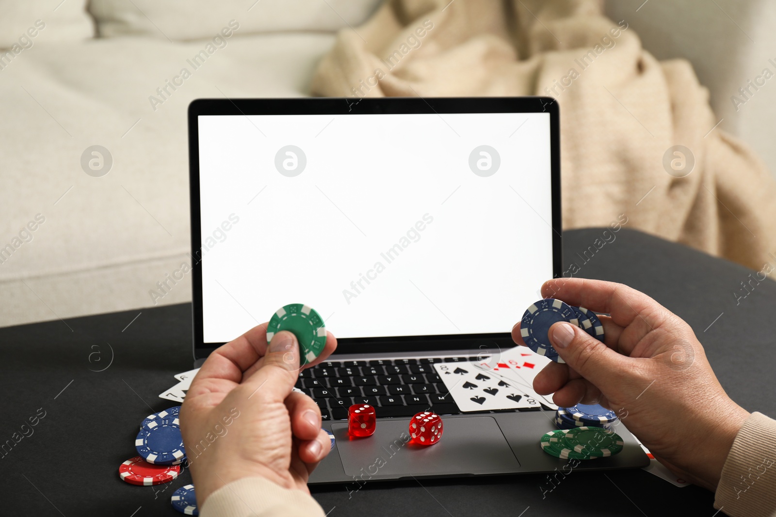 Photo of Man with laptop playing poker at black table, closeup. Online game