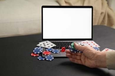 Photo of Man with laptop playing poker at black table, closeup. Online game