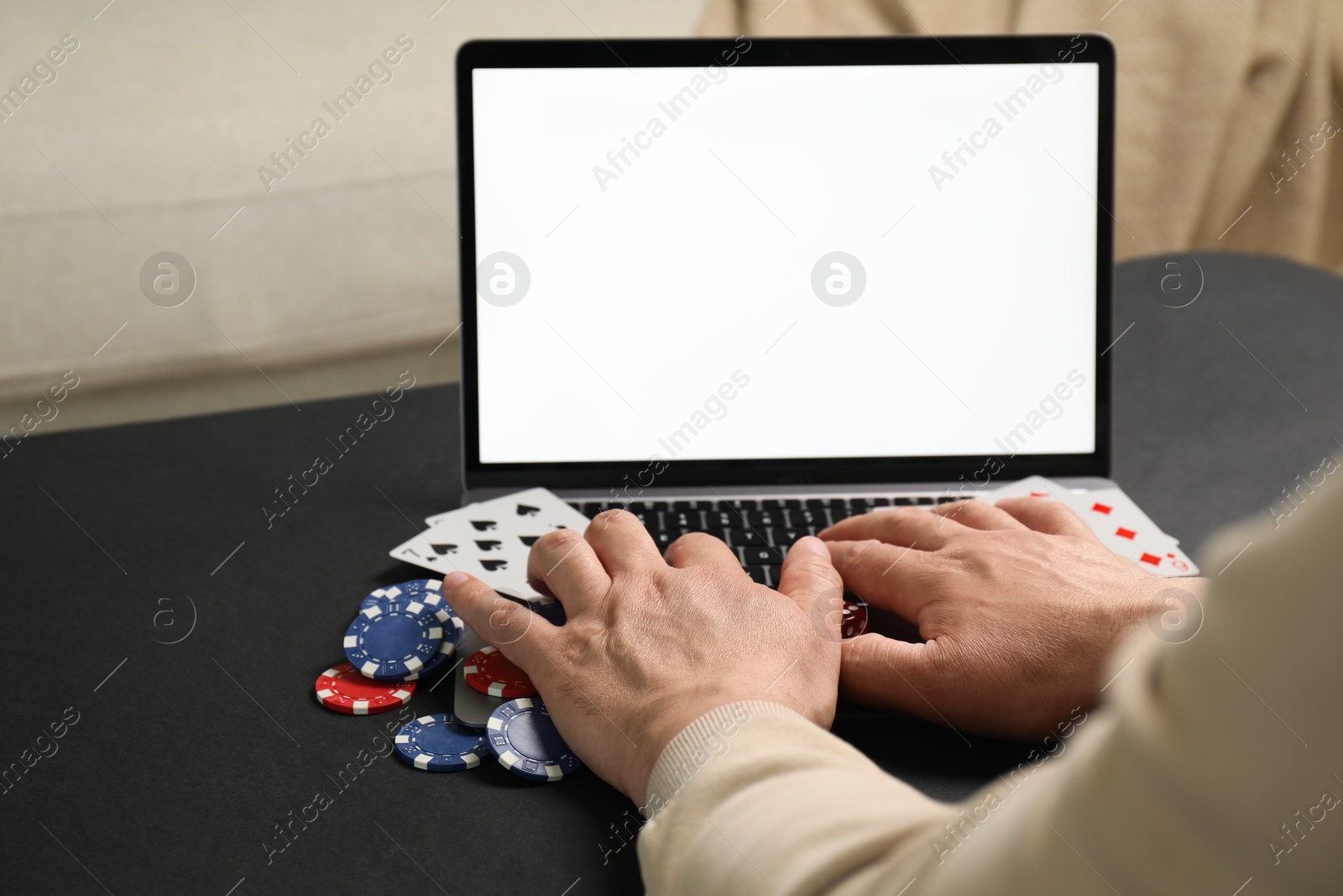 Photo of Man with laptop playing poker at black table, closeup. Online game