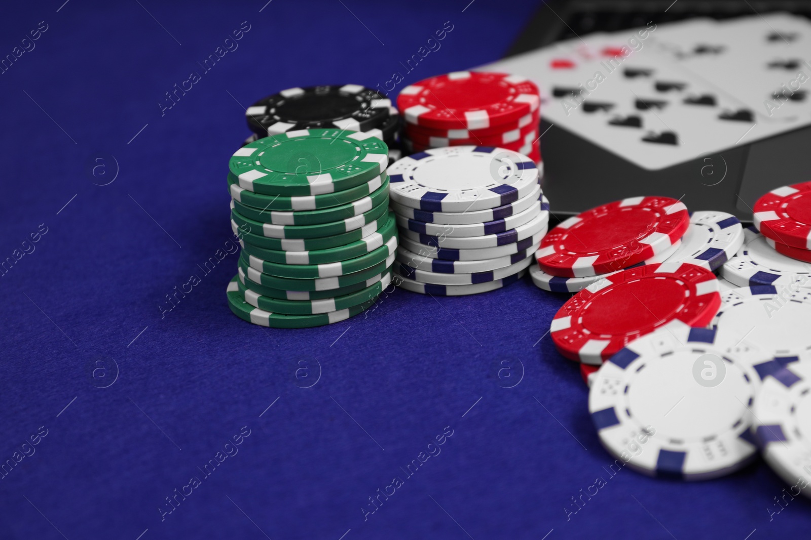 Photo of Poker chips and playing cards on blue table, closeup. Online game