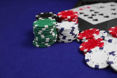 Photo of Poker chips and playing cards on blue table, closeup. Online game