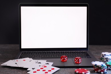 Photo of Laptop, poker chips, playing cards and dices on grey table. Online game