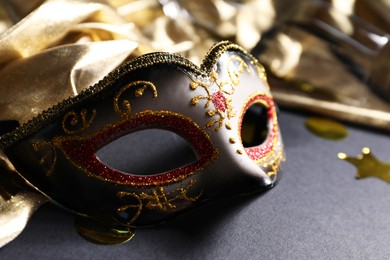 Beautiful carnival mask and silk fabric on black background, closeup