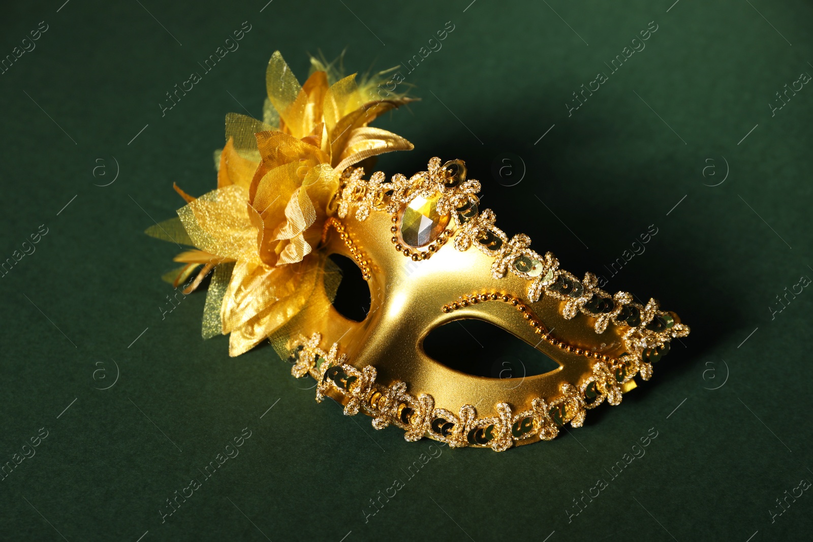 Photo of Beautiful golden carnival mask on green background