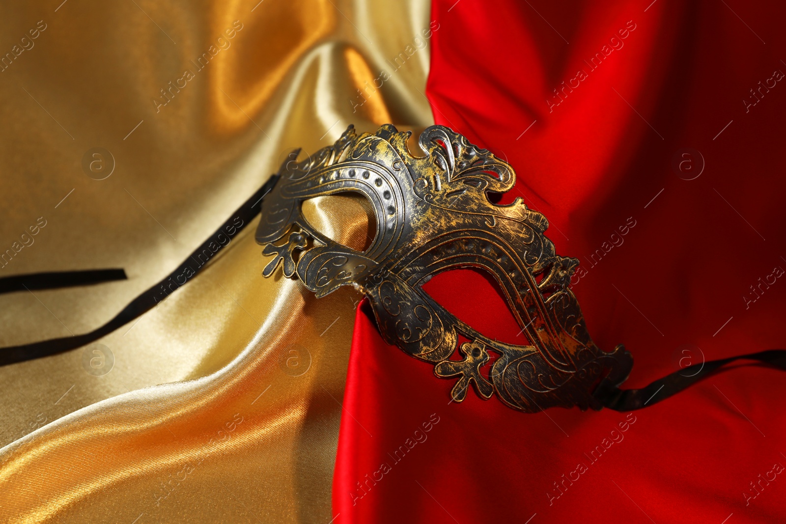 Photo of Beautiful carnival mask on silk fabric, closeup