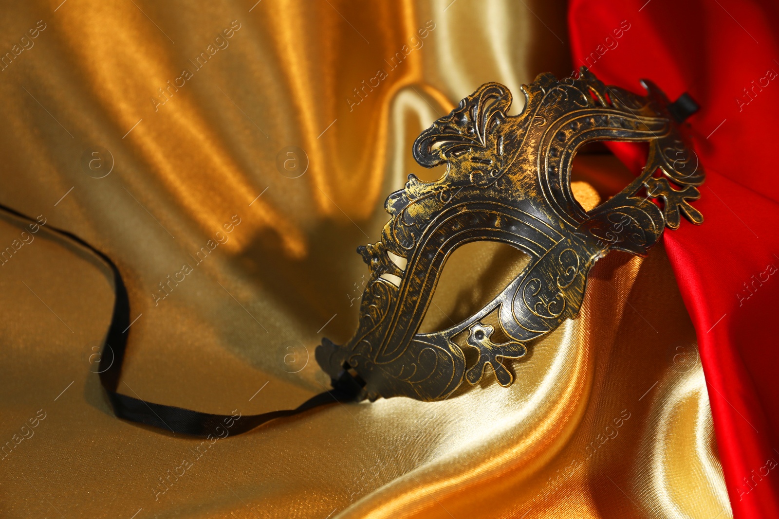 Photo of Beautiful carnival mask on silk fabric, closeup